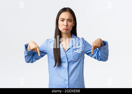 Enttäuscht verärgert und düster asiatische Mädchen beschwert, pouting traurig und Blick auf Kamera unzufrieden als Finger nach unten zeigen. Frau mag keinen Schlafsport Stockfoto