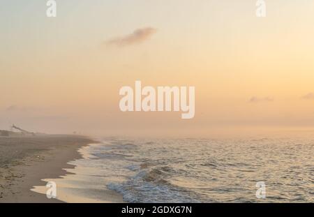 Nebliger Sonnenaufgang über dem Meer. Pastelltöne. Wunderschöne Landschaft. Sandstrand des Ozeans. Sonnenuntergang am Himmel. Wolken. Küste. Stockfoto