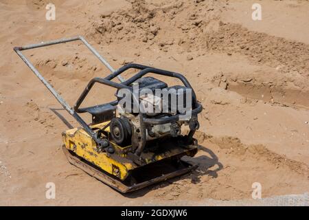 Manuelle Stampfmaschine zum Verdichten von Erde. Kiesbaumaschine auf der Baustelle. Sandlegemaschine Stockfoto