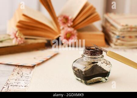 Tintenfass, Feder und getrocknete Rosen auf Vintage-Papier Hintergrund. Liebesbriefe Idee. Grüße zum Valentinstag. Stockfoto