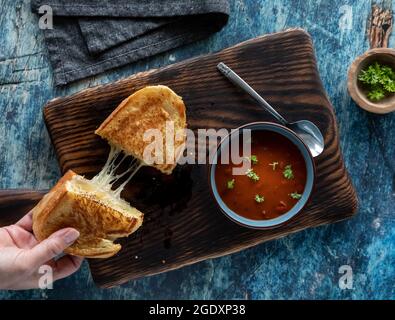 Nehmen Sie eine Hälfte eines gegrillten Käse-Sandwiches und eine Schüssel Tomatensuppe. Kombi-Konzept für Suppe und Sandwich. Stockfoto