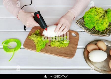 Floristen bei der Arbeit: Wie man Ostereier mit Moos und Bändern verziert. Frühlingsdekor-Ideen. Schritt für Schritt, Tutorial. Stockfoto