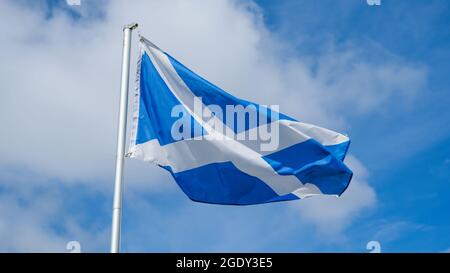 Das St. Andrew Cross oder Saltire, Nationalflagge Schottlands, fliegt im Wind mit einem blauen Himmel im Hintergrund Stockfoto