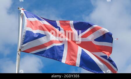 Eine Union Jack Flag, die von einem Fahnenmast am Himmel, der Nationalflagge des Vereinigten Königreichs von Großbritannien, fliegt Stockfoto