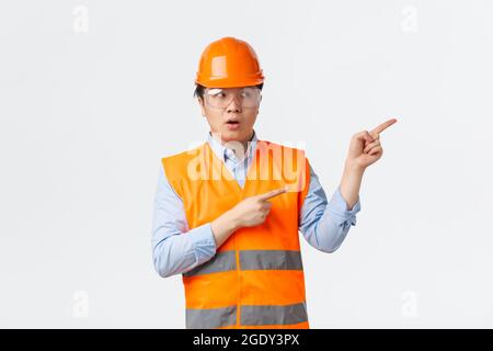 Baugewerbe und Industriearbeiter Konzept. Besorgt und zweifelhaft asiatischen männlichen Bauleiter, Ingenieur in Helm und reflektierende Kleidung Stockfoto