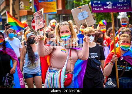 Braunschweig, 14. August 2021: Tanzende blonde junge Frau mit Zöpfen und einer Gesichtsmaske in den Farben des Regenbogens in der CSD Christopher Street Stockfoto