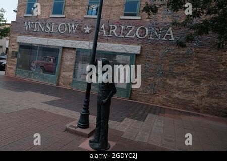 Winslow, Arizona, USA. August 2021. Standin' on the Corner Park in Winslow, Arizona. Eine Statue des Eagles-Mitglieds Glen Frey erinnert an den Hit Take IT Easy aus den 1960er Jahren mit der Zeile „nun, ich stehe an der Ecke in Winslow, Arizona, und es gibt einen so schönen Anblick zu sehen. Es ist ein Mädchen, mein Herr, in einer flachen Furt, die langsam einen Schau mich an. nimmt. Der Park enthält ein zweistöckiges Trompe-l'Ceil-Wandgemälde von John Hugh sowie eine Statue eines Mannes, der eine Gitarre vom Bildhauer Ron Adamson hält. Winslow ist ein beliebtes Touristenziel auf der berühmten alten Route 66, die sich im Navajo Reservat befindet. (C Stockfoto