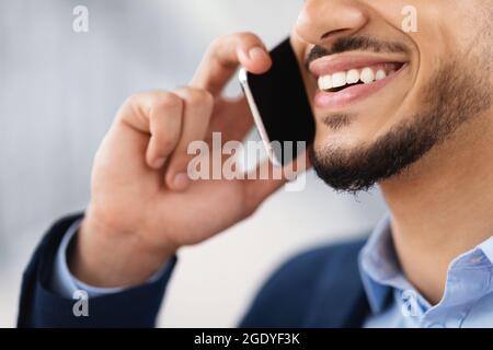 Telefonanruf. Nahaufnahme Eines Lächelnden Arabischen Mannes, Der Auf Dem Handy Spricht Stockfoto
