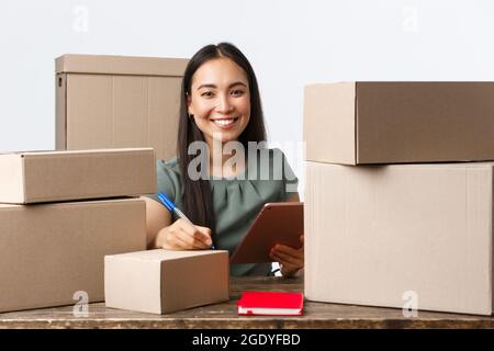 Kleinunternehmer, Startup und E-Commerce Konzept. Lächelnd erfolgreiche asiatische Geschäftsfrau mit eigenem Internet-Shop, online verkaufen, Versand schreiben Stockfoto