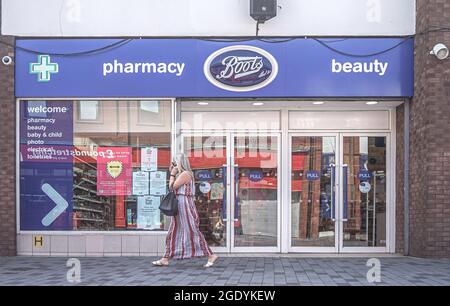 Lisburn, Großbritannien. Juli 2021. Eine Frau am Telefon geht an der Boots Pharmacy und dem Schönheitssalon in der Bow Street in Lisburn vorbei. (Foto von Michael McNerney/SOPA Images/Sipa USA) Quelle: SIPA USA/Alamy Live News Stockfoto