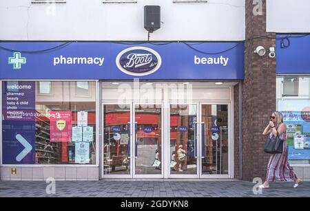 Lisburn, Großbritannien. Juli 2021. Eine Frau am Telefon geht an der Boots Pharmacy und dem Schönheitssalon in der Bow Street in Lisburn vorbei. (Foto von Michael McNerney/SOPA Images/Sipa USA) Quelle: SIPA USA/Alamy Live News Stockfoto