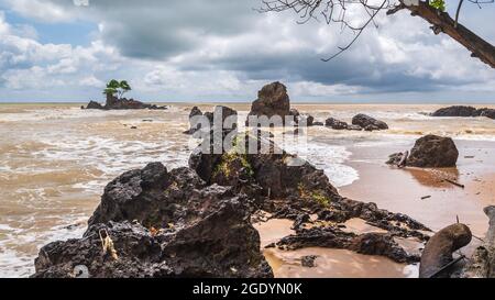 Schöne unberührte Natur in Axim mit einem einsamen Baum wächst auf einer kleinen Steininsel und Strände mit schönen Felsen, die von den Gewässern des We gebildet Stockfoto