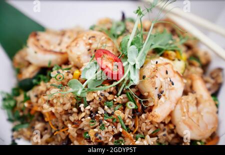 Gebratener Reis aus nächster Nähe mit Garnelen und Gemüse, zubereitet im chinesischen Wok als vegetarisches Fastfood auf weißem Hintergrund. Chinesisches Konzept für gesundes Street Food. Hochwertige Bilder Stockfoto