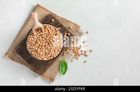 Kichererbsen in einer Schüssel mit einer Holzlöffel auf grauem Hintergrund. Stockfoto
