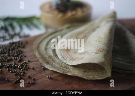 Eiweißreicher Moong-Bohne-Crepe, lokal als Pesarattu bekannt. Es sieht aus wie Dosa, aber nicht mit fermentiertem Teig. Serviert zusammen mit Kokosnuss chu gefaltet Stockfoto