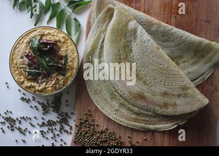 Eiweißreicher Moong-Bohne-Crepe, lokal als Pesarattu bekannt. Es sieht aus wie Dosa, aber nicht mit fermentiertem Teig. Serviert zusammen mit Kokosnuss chu gefaltet Stockfoto