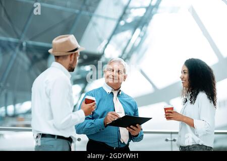 Multinationale Gruppe von Geschäftsleuten, die über Geschäftsdokum diskutieren Stockfoto