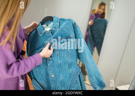 Junge Frau versuchen, Kleidung in Ankleidezimmer mit Spiegel im Geschäft. Stockfoto