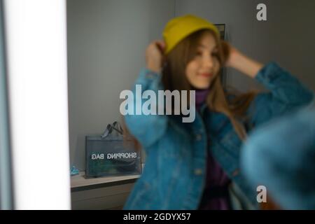 Junge Frau versuchen, Kleidung in Ankleidezimmer mit Spiegel im Geschäft. Stockfoto