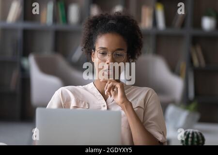 Nachdenkliche afroamerikanische Frau arbeiten auf Laptop denken Stockfoto