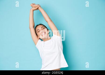 Portrait von sorglos und entspannt, schöne asiatische Mädchen schließen Augen und Strecken Hände nach oben mit glücklichem Lächeln, Gefühl frisch und fröhlich nach Stockfoto