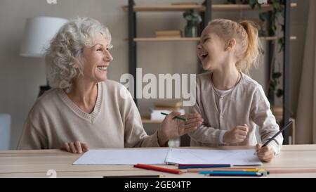 Lächelnde Großmutter und Enkelin zeichnen sich zusammen im Album Stockfoto