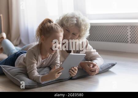 Glückliche alte Großmutter und kleine Enkelin sprechen auf Videoanruf Stockfoto