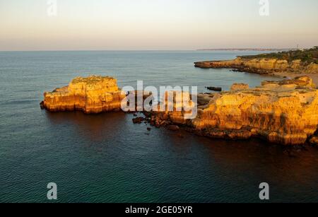 Atlantische Meeresküste in Portugal Algarve bei Albufeira, felsige Klippen mit sichtbarer Erosion, Landschaftsaufnahme bei Sonnenaufgang. Wunderschöne Holida Stockfoto