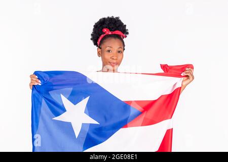 Eine lächelnde Latina-Frau, die die Flagge von Puerto Rico hält, während sie die Kamera anschaut Stockfoto