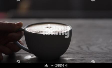 Gießen Sie gestreamte Milch in eine blaue Tasse, um Cappuccino mit Platz zum Kopieren und breitem Foto zuzubereiten Stockfoto