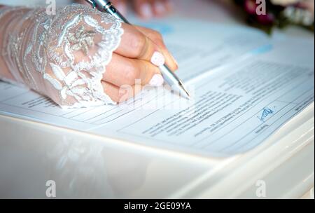 Dnepropetrovsk, Ukraine - 08.12.2016: Hochzeitszeremonie. Das Brautpaar hinterlässt seine Unterschriften. Die Hand der Braut. Stockfoto