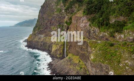 Wasserfall, der von vulkanischen Klippen in den Ozean fällt. Stockfoto