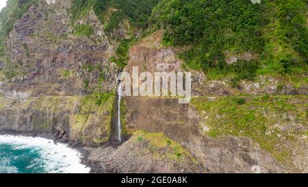 Wasserfall, der von vulkanischen Klippen in den Ozean fällt. Stockfoto