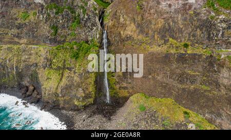 Wasserfall, der von vulkanischen Klippen in den Ozean fällt. Stockfoto