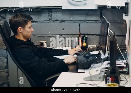 Junger Mann Programmierer Gamer sitzt auf einem Stuhl mit Computer-Desktop in der Nähe von Virtual-Reality-Brille, vr Brille Headset. Stockfoto