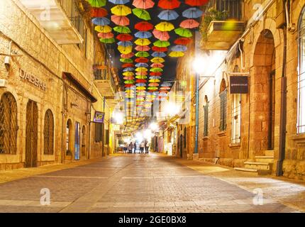 Bunte Regenschirme über der Sםlomon-Straße bei Nacht, Jerusalem, Israel. Stockfoto