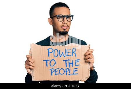 Junger afroamerikanischer Mann, der die Macht an die Menschen hält, bannerlos und verwirrt Ausdruck. Zweifel Konzept. Stockfoto