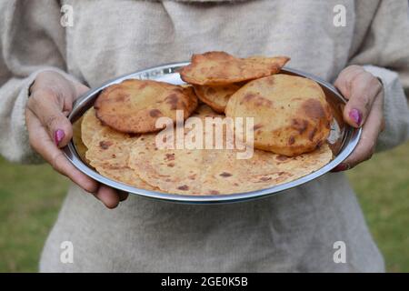 Weibchen hält Thaali des indischen Fastfood-Artikels Rajgira paratha und puri zum Mittag- oder Abendessen während Fastentage wie navratri, Mahashivratri, Ekada Stockfoto