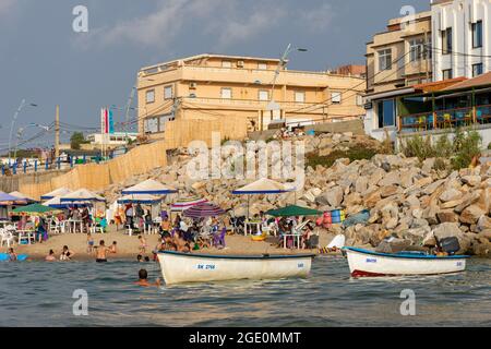 Blick auf zwei Boote und Familien, die Spaß am Strand haben, Kinder, die im Wasser spielen, Skikda, Algerien. Stockfoto