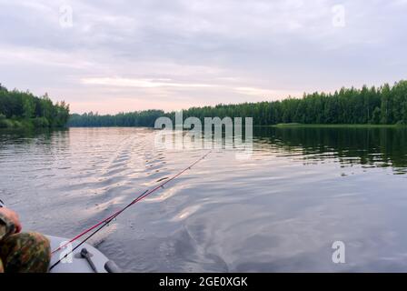 Ein Fischer auf einem aufblasbaren Boot fängt Fische beim Spinnen. Der Prozess des Trolling auf dem See Stockfoto