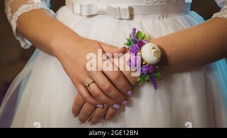Die Hände der Braut mit dekorativem Boutonniere auf dem Hochzeitskleid in Nahaufnahme Stockfoto