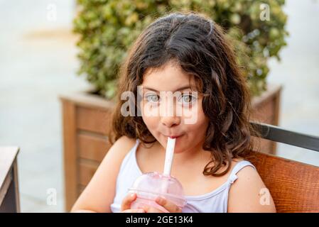 Kleines lateinisches Mädchen trinkt Milchshake mit lustigen Ausdruck. Stockfoto