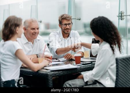 Junge Geschäftsleute schütteln sich bei einer Tagung in einem Business-Center die Hände. Stockfoto