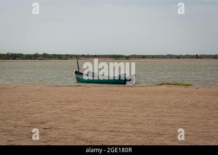 Ryohacha, La Guajira, Kolumbien - 30 2021. Mai: Zwei kleine weiße und grüne Boote, die am Sandstrand von Camarones an einen Holzstock gebunden sind Stockfoto