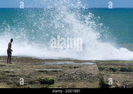 Salvador, Bahia, Brasilien - 17. Oktober 2015: Menschen riskieren ihr Leben auf Felsen mit starken Wellen. Stockfoto