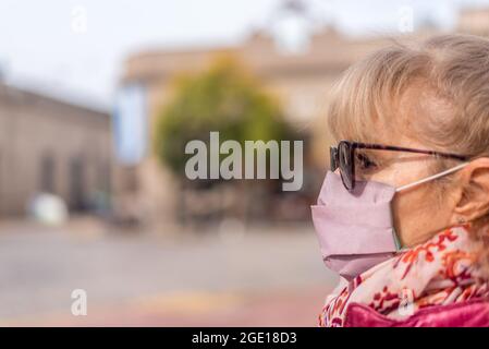 Nahansicht einer erwachsenen Frau, die draußen eine schützende Gesichtsmaske und eine Sonnenbrille verwendet. Selektiver Fokus. Stockfoto