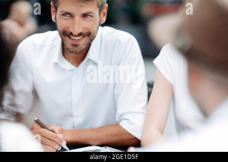 Lächelnder Geschäftsmann, der an einem Schreibtisch sitzt. Stockfoto