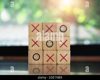 Drei lächelnde Gesicht Symbole auf tic tac Zehe Holzblock Spiel auf Holztisch auf grünem Natur Hintergrund. Gewinner, Strategie- und Geschäftszielkonzept. Stockfoto