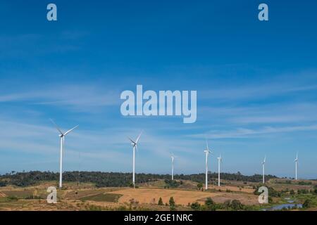 Windturbinen, die Strom über dem Hintergrund des blauen Himmels erzeugen. Windmühle auf herbstlicher Berglandschaft. Stockfoto