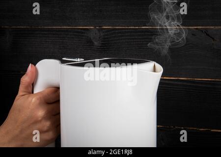 Wasserkocher in der Hand einer Frau. Stockfoto